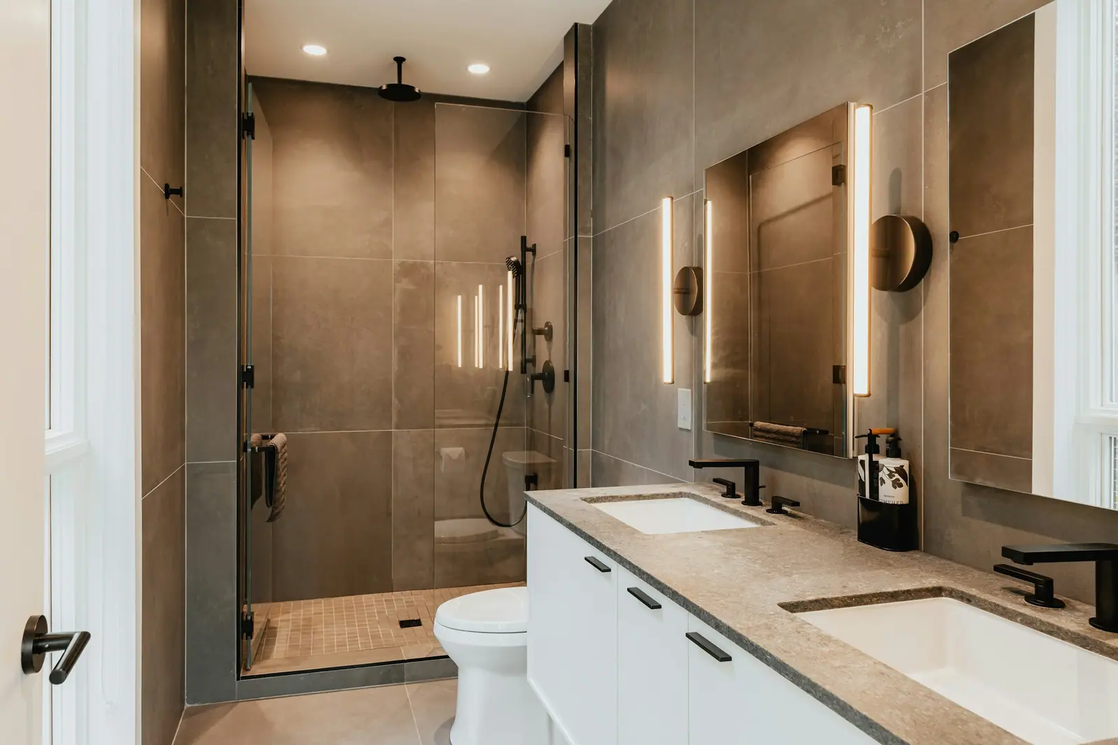 New bathroom with brown-toned tile and a glass shower enclosure